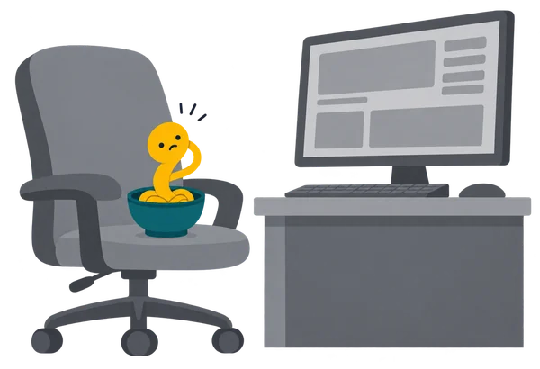 Noodle in its bowl on a giant grey office chair, too small to reach a huge grown-up computer